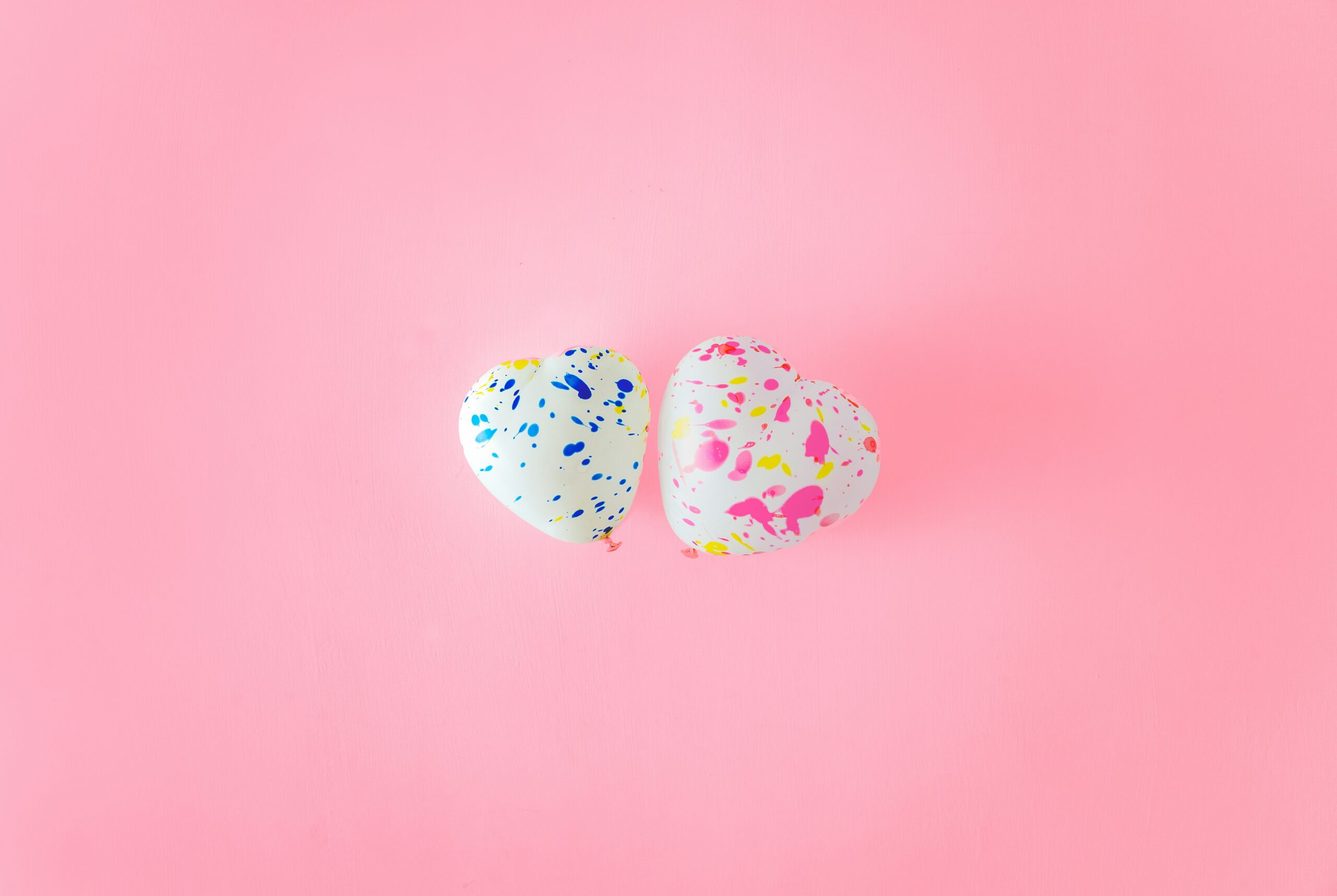 Two white Balloon hearts against pink background